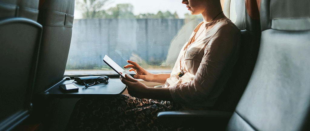 Une personne voyageant dans un train regarde une tablette.