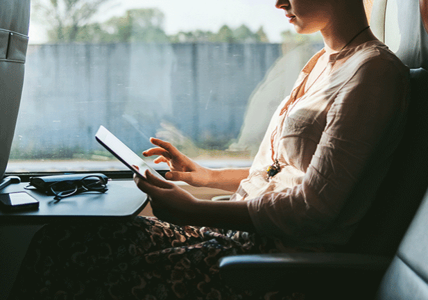 Une personne voyageant dans un train regarde une tablette.