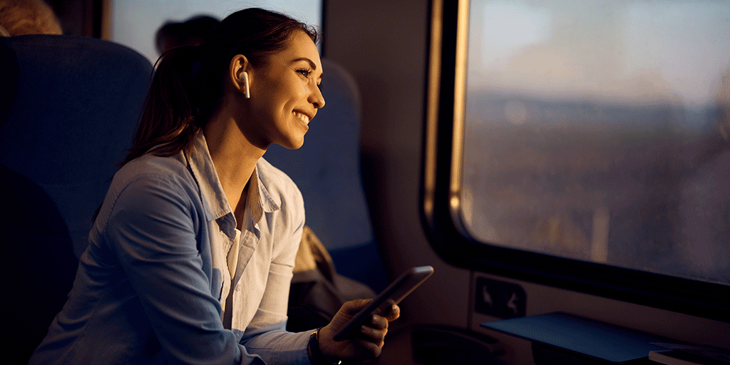 Une personne voyageant dans un train, tout en tenant un smartphone.